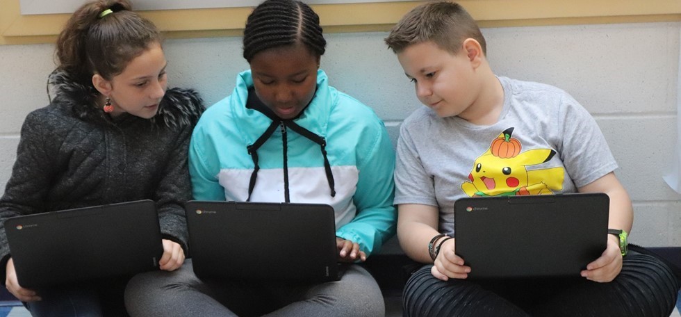 MHE students in the hallway using their laptops 
